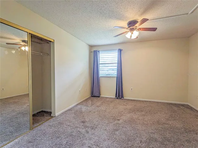 an empty room with closet and a chandelier fan