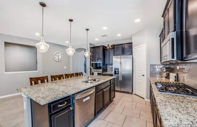 a kitchen with stainless steel appliances granite countertop a sink a stove and a refrigerator