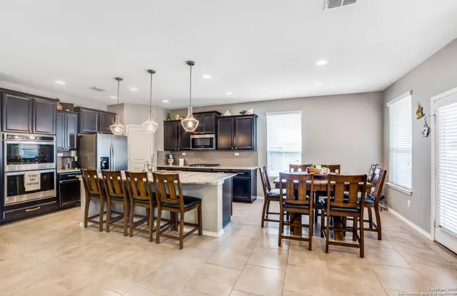 a kitchen with appliances a dining table chairs and granite counter tops