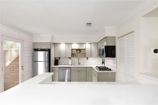a large white kitchen with a sink a refrigerator and a stove top oven with wooden floor