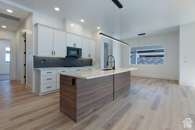 3145 Snow Cyn Road Hurricane, UT 84737 - Photo 7 of 38 Kitchen with light wood-style floors, light countertops, an island with sink, backsplash, and white cabinetry