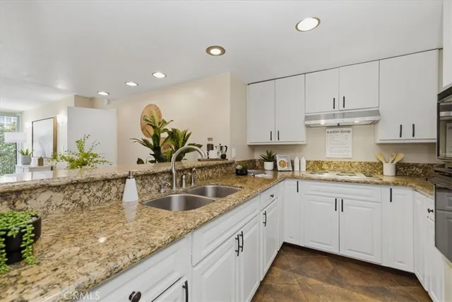 a kitchen with stainless steel appliances granite countertop a stove a sink and white cabinets