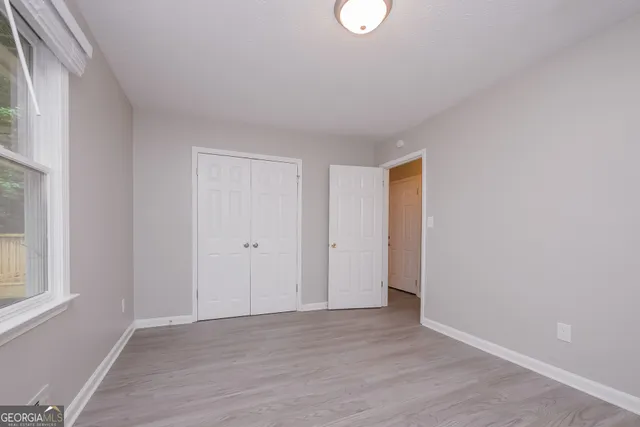 a view of an empty room with wooden floor and a window