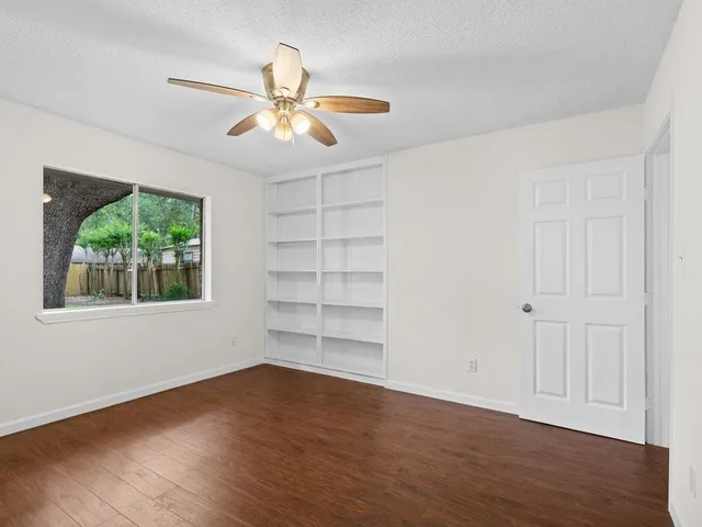 a view of an empty room with a window and wooden floor