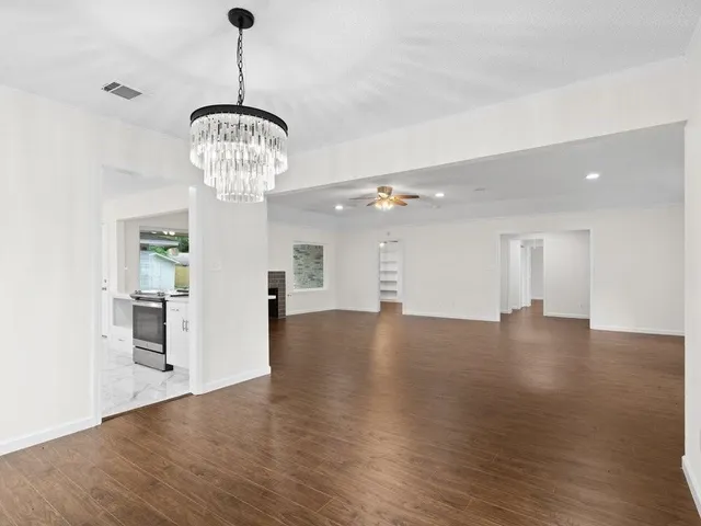 a view of a room with wooden floor chandelier and windows