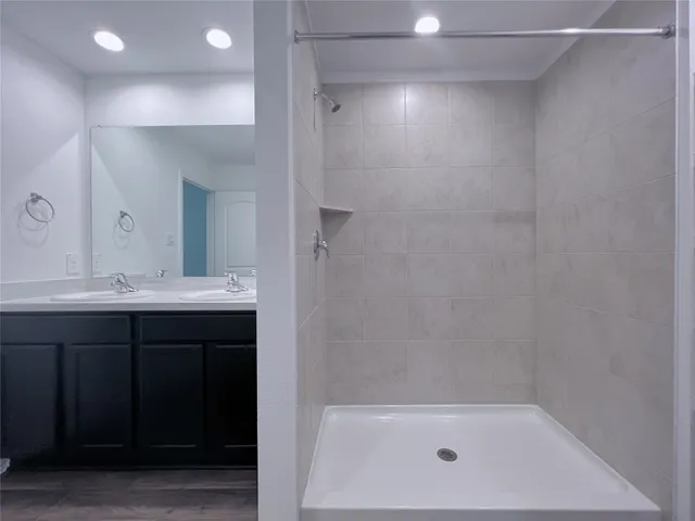 a bathroom with a bathtub shower sink vanity and mirror