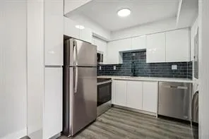 a kitchen with stainless steel appliances granite countertop a refrigerator a stove a sink and white cabinets