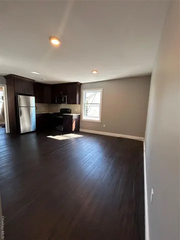 a view of empty room with kitchen and window