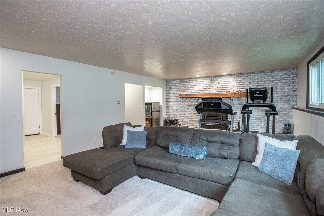3434 Hamlin Road Medina, OH 44256 - Photo 28 of 37 Family room featuring brick wall, a textured ceiling, and light colored carpet