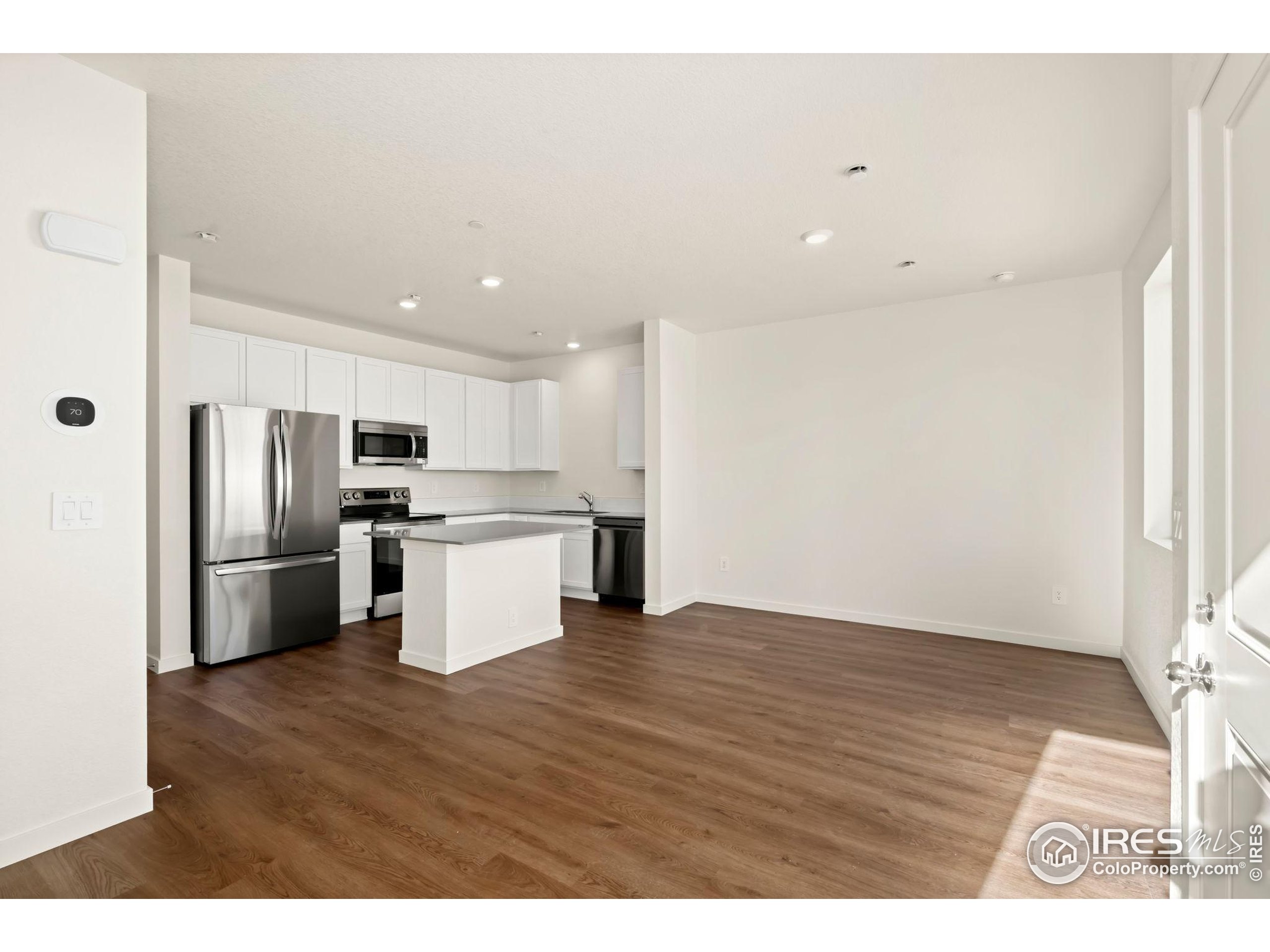 3904 Net Street Evans, CO 80620 - Photo 5 of 14 a kitchen with stainless steel appliances wooden floor and a refrigerator