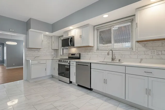 a kitchen with white cabinets appliances and a sink