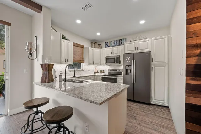 a kitchen with stainless steel appliances granite countertop a refrigerator a sink a stove a dining table and chairs