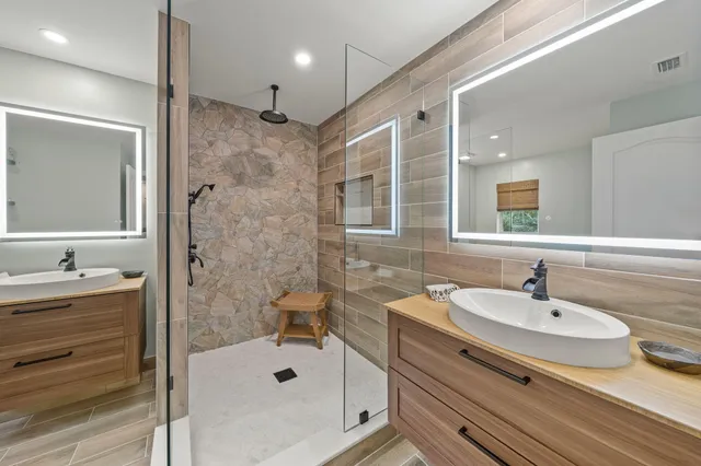 a bathroom with a sink double vanity granite tub shower and a mirror
