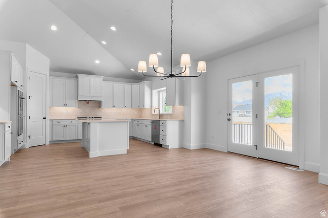11711 South Halls Crk Road Draper, UT 84020 - Photo 14 of 31 Kitchen featuring vaulted ceiling, a kitchen island, a chandelier, tasteful backsplash, and white cabinets