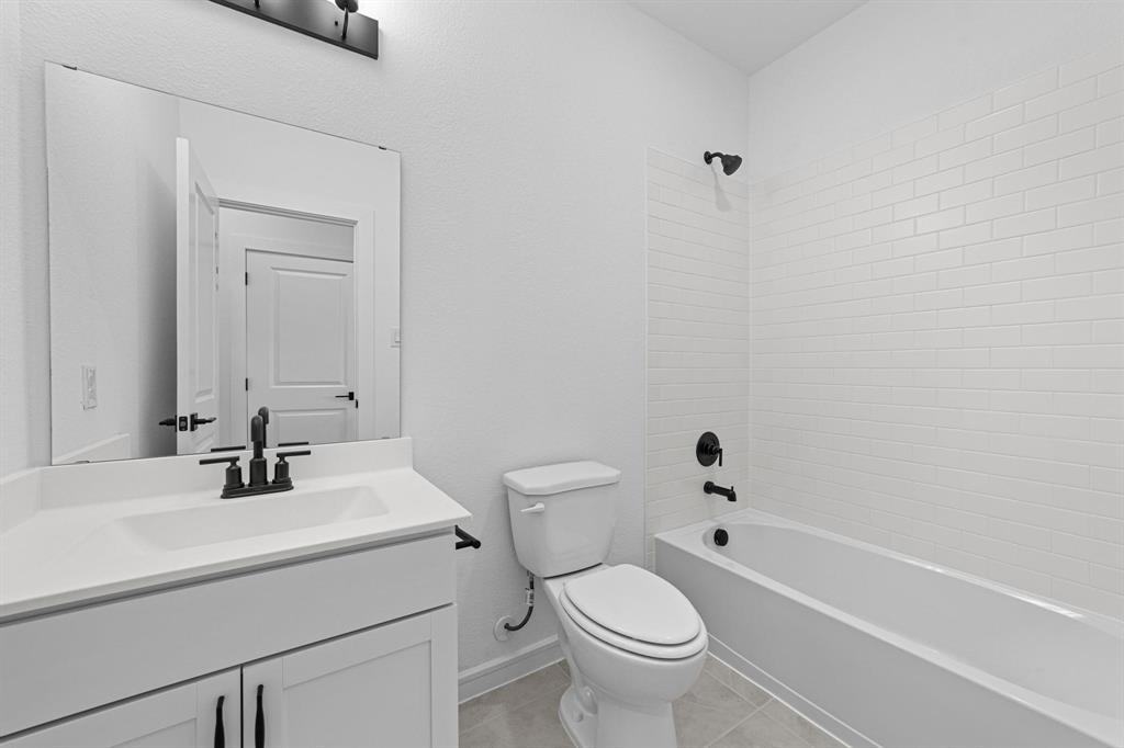 1509 Hamilton Street Howe, TX 75459 - Photo 19 of 23 Full bathroom featuring tile patterned flooring, toilet, vanity, baseboards, and washtub / shower combination
