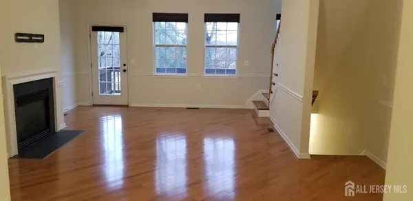 a view of an empty room with wooden floor and a fireplace