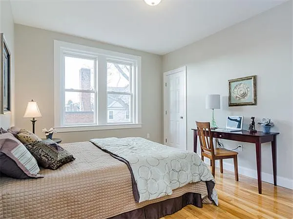 a bedroom with a bed a table and chair with a large windows