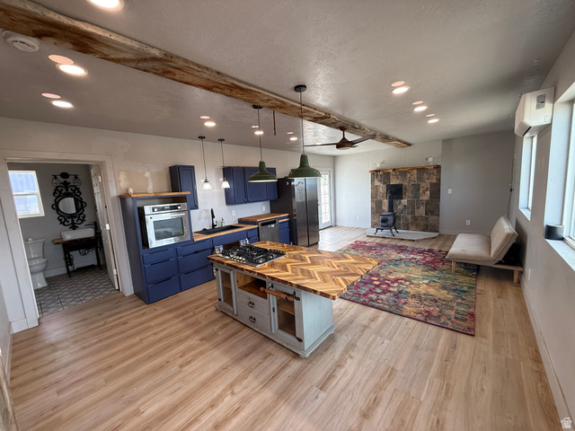 14183 High Mesa Loop Duchesne, UT 84021 - Photo 32 of 56 Kitchen with blue cabinets, a wood stove, beamed ceiling, healthy amount of natural light, and light wood-style flooring