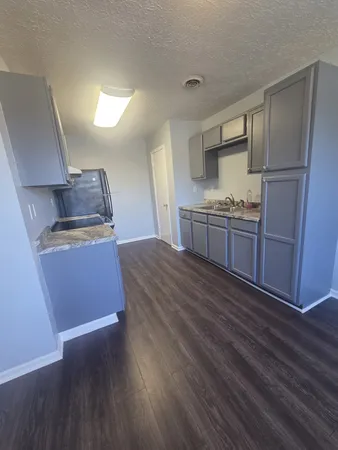 a kitchen with granite countertop a refrigerator and a stove top oven