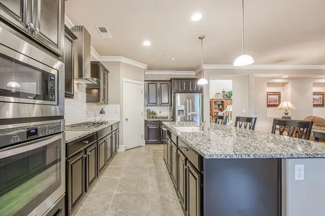 a kitchen with stainless steel appliances granite countertop a sink refrigerator and cabinets