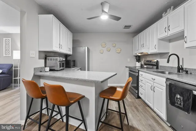 a kitchen with stainless steel appliances granite countertop a table chairs sink and cabinets