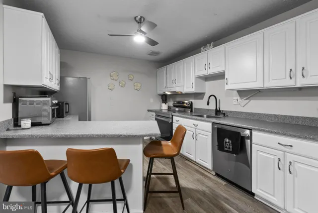 a kitchen with stainless steel appliances granite countertop a stove a sink dishwasher a microwave oven and a white cabinets