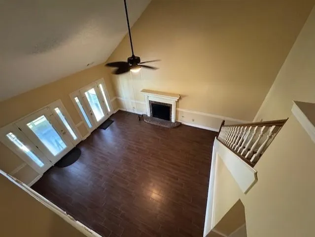 a view of an empty room with wooden floor and a ceiling fan