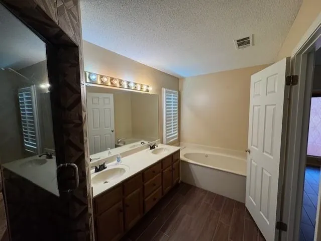 a bathroom with a double vanity sink a mirror and a bathtub