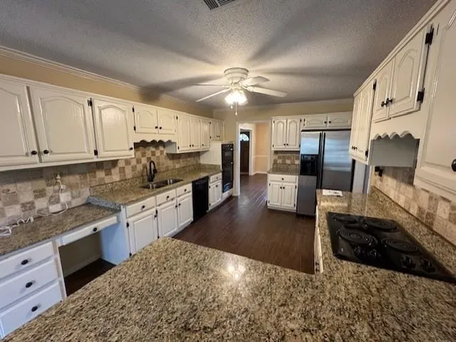a kitchen with granite countertop a stove a sink and a refrigerator