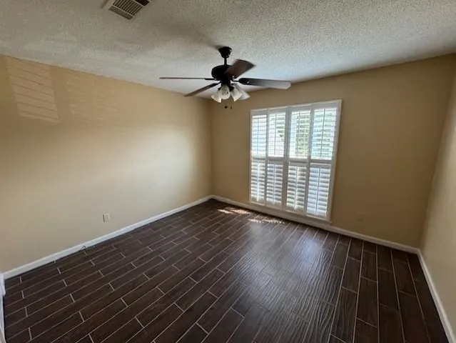 a view of a room with wooden floor ceiling fan and window