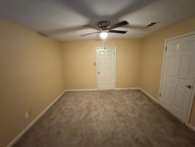 an empty room with a chandelier fan and a window