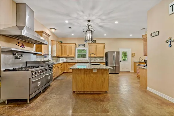 a kitchen with stainless steel appliances granite countertop a sink a stove and a refrigerator