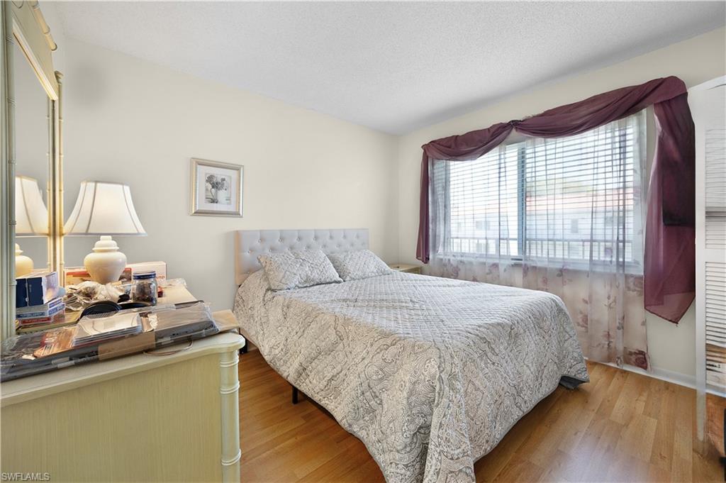 5 High Point Circle West, Unit 313 Naples, FL 34103 - Photo 4 of 24 a bedroom with a bed and wooden floor