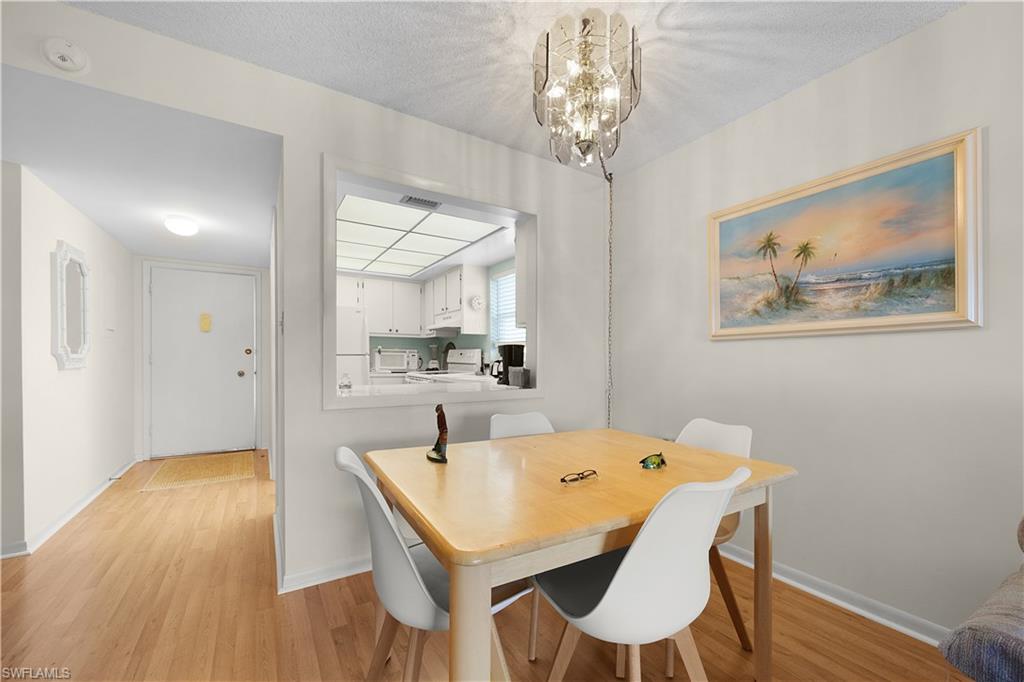 5 High Point Circle West, Unit 313 Naples, FL 34103 - Photo 5 of 24 a view of a dining room with furniture and wooden floor