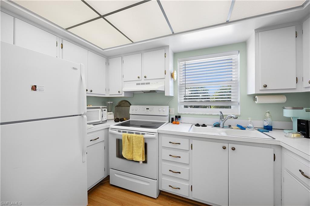 5 High Point Circle West, Unit 313 Naples, FL 34103 - Photo 9 of 24 a kitchen with a refrigerator sink stove and cabinets