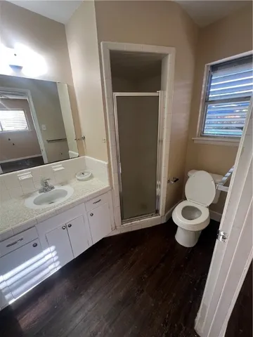 a bathroom with a granite countertop sink toilet a large mirror a vanity and a window