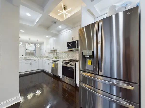 a kitchen with stainless steel appliances granite countertop a refrigerator a stove and a sink with wooden floor