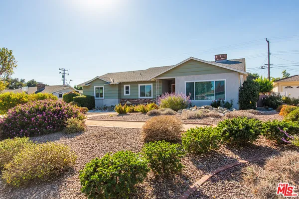 a front view of a house with a yard and potted plants