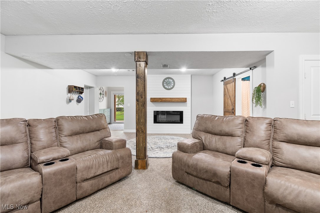 440 Abbyshire Road Green, OH 44319 - Photo 22 of 33 Carpeted living room featuring a barn door, a textured ceiling, and a large fireplace