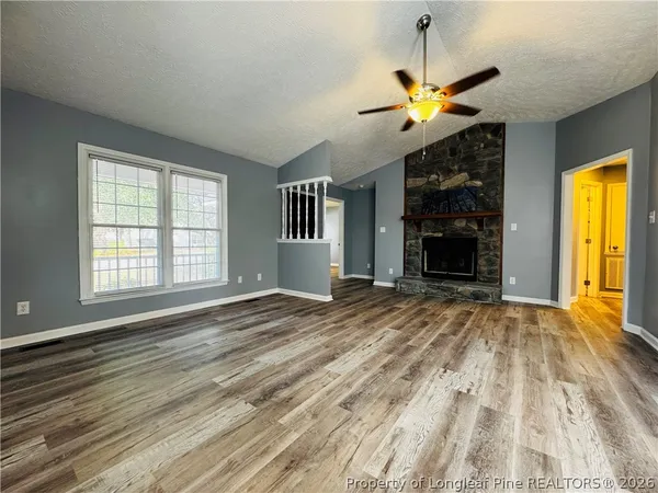 a view of an empty room with window and wooden floor