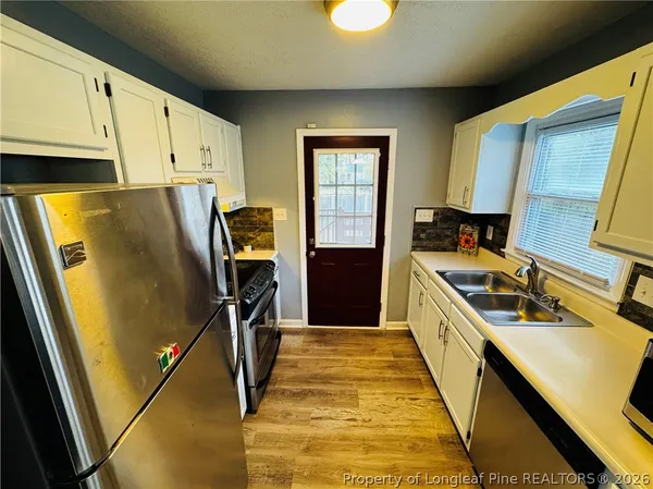a kitchen with stainless steel appliances a refrigerator a sink and white cabinets
