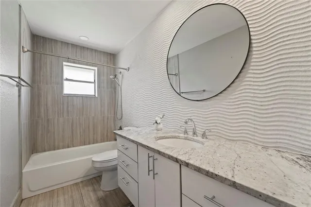 a bathroom with a granite countertop sink a toilet and a bathtub