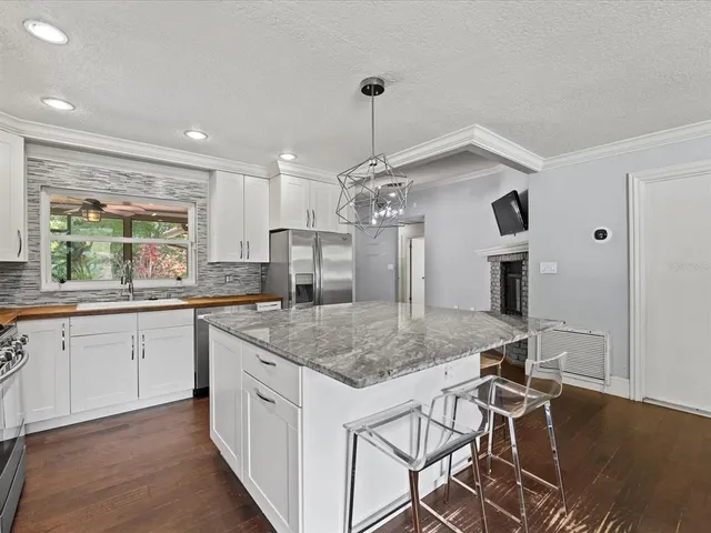 a kitchen with stainless steel appliances granite countertop a sink a stove a dining table and chairs