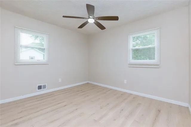 an empty room with wooden floor and windows