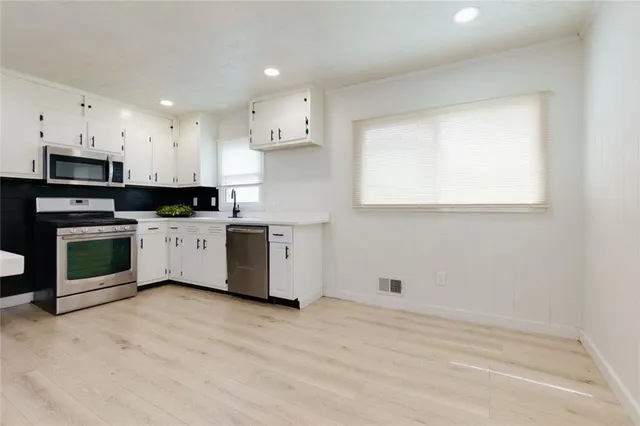a kitchen with white cabinets and stainless steel appliances