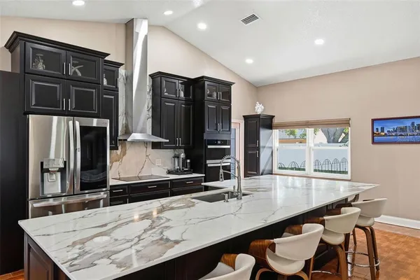 a kitchen with stainless steel appliances kitchen island granite countertop a table chairs in it and wooden floors