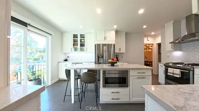 a kitchen with stainless steel appliances granite countertop a stove top oven a sink dishwasher and white cabinets next to a window