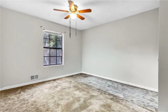 an empty room with windows and chandelier fan
