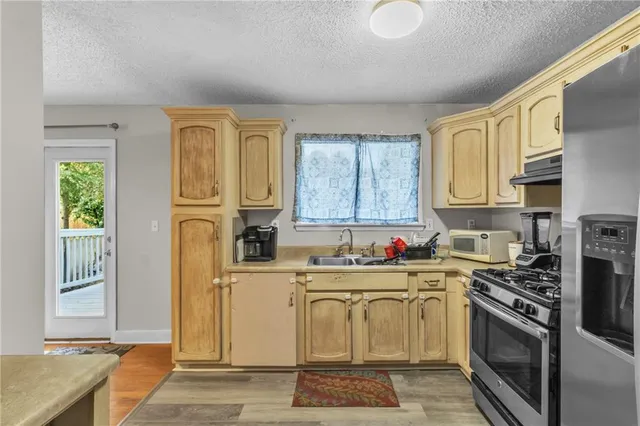a kitchen with stainless steel appliances granite countertop a stove a sink and a microwave