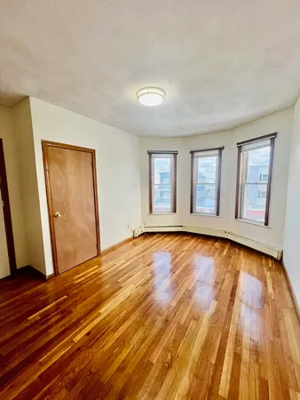 a view of an empty room with wooden floor and window